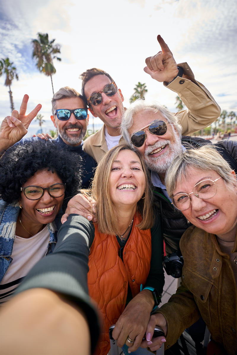 Group diverse cheerful middle-aged tourist friends posing smiling taking a photo selfie embracing.