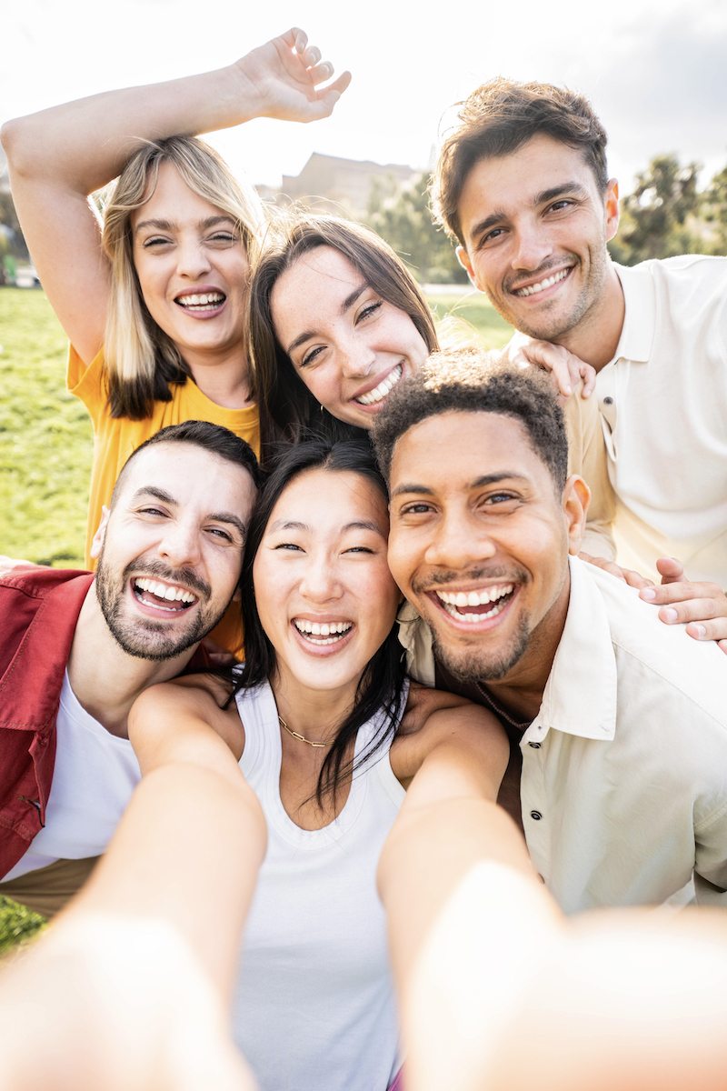 Multiracial young people taking selfie pic with smart mobile phone device - Vertical photo of happy friends smiling at camera - Life style concept with guys and girls hanging out on summer day