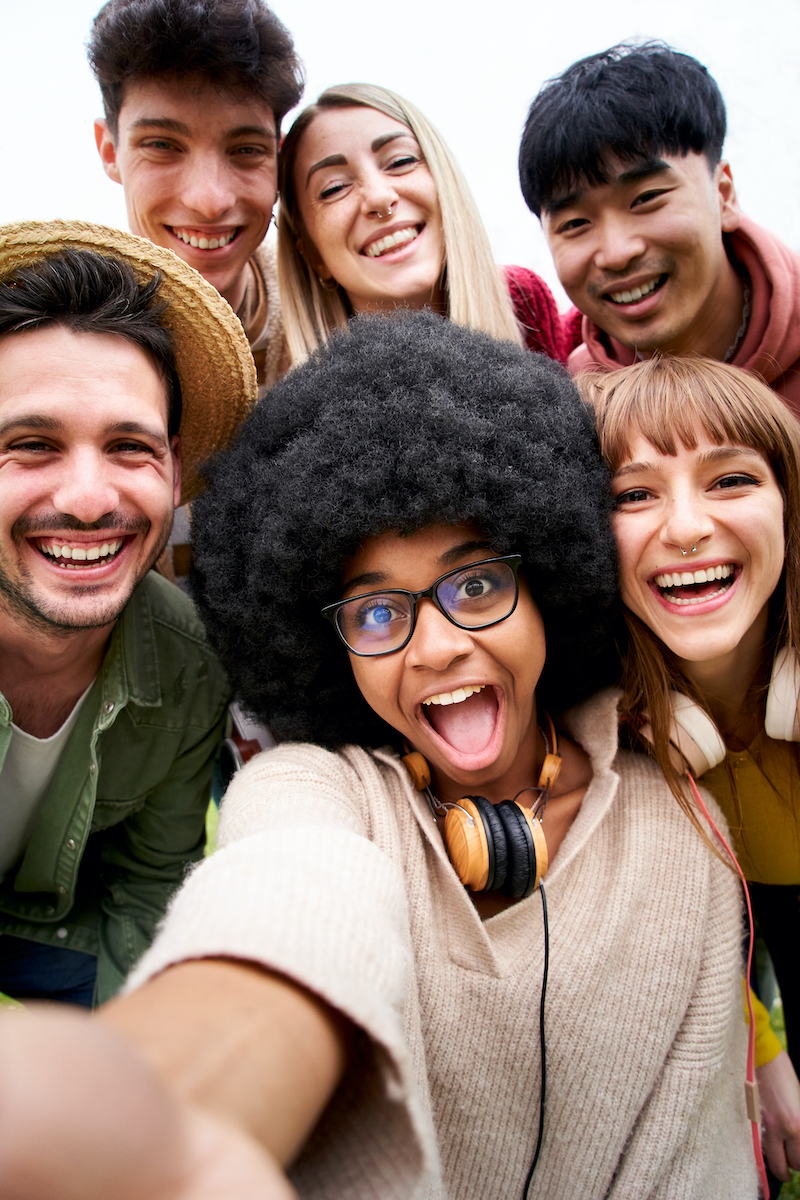 Vertical photo of Cheerful group of friends taking smiling selfie. Group of young people having fun together outdoors at park in the city enjoying travel in vacation holidays. High quality photo